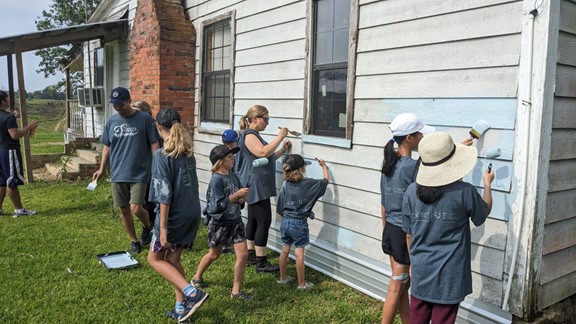 A group of people painting the outside of a house